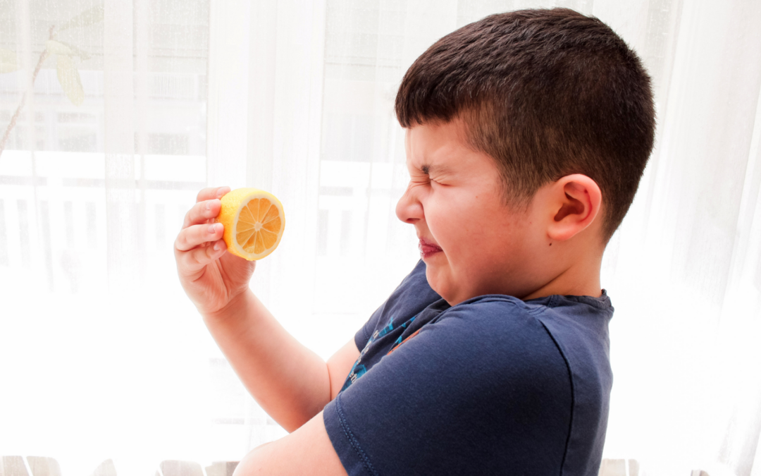 boy grimacing while holding a lemon